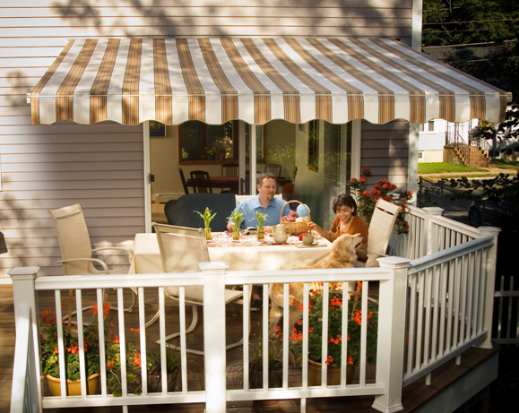 A married couple, and their dog, enjoying their morning on their Pennsylvania deck, beneath the shade of a Sunesta retractable awning.